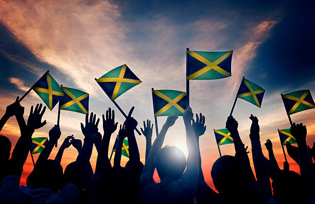 group of people waving flag of jamaica in back lit